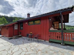 ein rotes Haus mit einem Tisch und Stühlen im Freien in der Unterkunft Holiday Home Staksholmen - SOW725 by Interhome in Konsmo