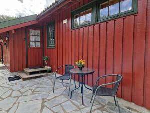 eine Terrasse mit 2 Stühlen und einem Tisch vor einer roten Wand in der Unterkunft Holiday Home Staksholmen - SOW725 by Interhome in Konsmo