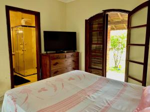 een slaapkamer met een bed en een flatscreen-tv bij Guaru Surf Hostel in Guarujá