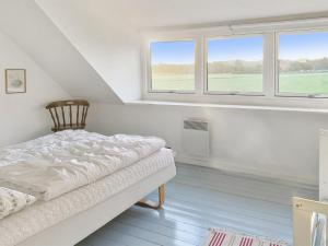 um quarto branco com uma cama e 2 janelas em Holiday Home Torbjörn - 2-5km from the sea in Bornholm by Interhome em Gudhjem