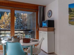 una cucina con tavolo, sedie e forno a microonde di Apartment Mont-Fort-29 by Interhome a Siviez