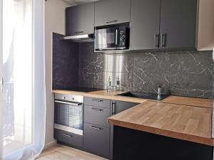 uma cozinha com armários cinzentos e um micro-ondas em Appart Hotel Cinéma Perpignan em Perpignan
