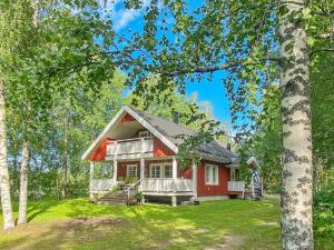 a red house with a porch in the woods at Holiday Home Casa rantapirtti by Interhome in Jyväskylä