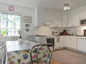 a kitchen with white cabinets and a table with chairs at Holiday Home Casa rantapirtti by Interhome in Jyväskylä +18 photos