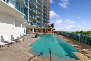 a swimming pool with chairs and a building at Sterling Breeze 1803 in Panama City Beach