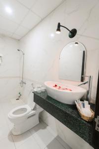 ein Badezimmer mit einem Waschbecken, einem WC und einem Spiegel in der Unterkunft Lotus Rock Hotel Đà Nẵng in Đà Nẵng