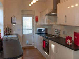 a kitchen with white cabinets and a black counter top at 2 Bed in Ystragynlais BN247 in Crynant