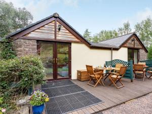 Ce cottage dispose d'une terrasse en bois avec une table et des chaises. dans l'établissement 2 Bed in Llangenny BN284, à Llangenny