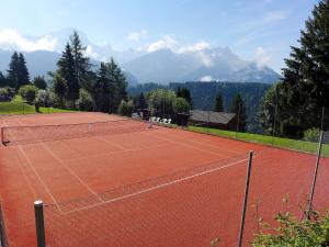 a tennis court with mountains in the background at Apartment Régina A20 by Interhome in Arveyes