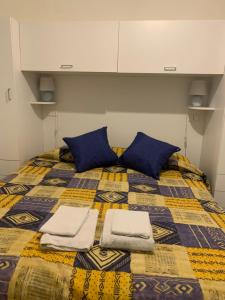 un letto con cuscini blu e asciugamani di La casa a mare a Cetara