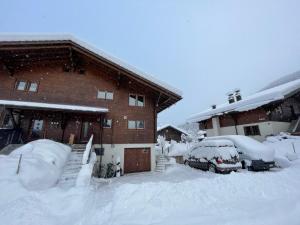 a snow covered house with cars parked in front of it at Apartment Chalet Ilge by Interhome in Lenk