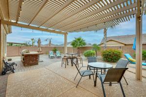 a patio with tables and chairs under a wooden pergola at Beautiful Goodyear Home with Pool and Gas Grill! in Goodyear