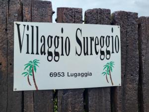 a sign on a fence with a palm tree at Apartment Villaggio Sureggio - App- C1 by Interhome in Lugaggia