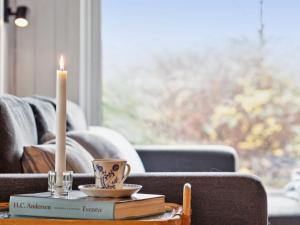 a candle and books on a coffee table in front of a couch at Holiday Home Benthe - 200m from the sea in Funen by Interhome in Humble
