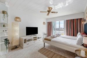 a white bedroom with a bed and a television at Apto El Dorado 929 in Playa de las Americas
