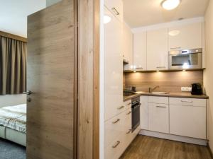 a kitchen with white cabinets and a wooden wall at Apartment Top 6 - Panorama by Interhome in Ischgl