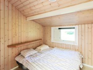 uma cama num quarto de madeira com uma janela em Holiday Home Fredrike - all inclusive - 500m from the sea by Interhome em Vester Sømarken