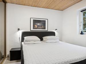 una camera da letto bianca con un letto con lenzuola e cuscini bianchi di Apartment Annica - 900m from the sea in NW Jutland by Interhome a Blokhus