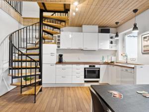 a kitchen with white cabinets and a spiral staircase at Apartment Annica - 900m from the sea in NW Jutland by Interhome in Blokhus