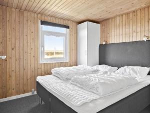 een slaapkamer met een groot wit bed en een raam bij Holiday Home Månviva - 500m from the sea in NW Jutland by Interhome in Løkken
