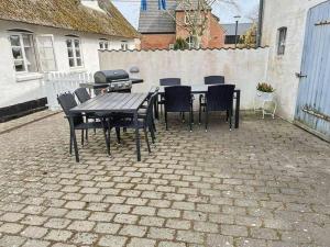 een patio met een tafel en stoelen en een grill bij Holiday Home Maelle - 25km from the sea in Western Jutland by Interhome in Højer