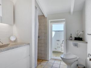 a white bathroom with a toilet and a shower at Holiday Home Annrike - 400m from the sea in NW Jutland by Interhome in Saltum