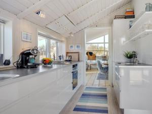uma cozinha com bancadas brancas e uma sala de jantar em Holiday Home Annrike - 400m from the sea in NW Jutland by Interhome em Saltum