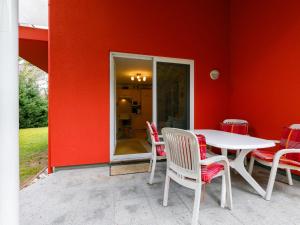 a table and chairs in front of a red wall at Apartment Meerzeit by Interhome in Trassenheide
