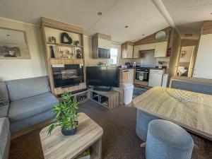 a living room with a blue couch and a table at Spacious Caravan On The Suffolk Coast With Outside Decking Too Ref 20044bs in Hopton on Sea