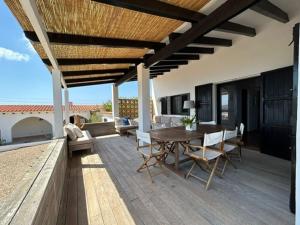 un patio al aire libre con mesa de madera y sillas en Holiday Home Nueva by Interhome, en Sant Ferran de Ses Roques