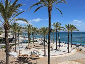 Blick auf einen Strand mit Palmen und das Meer in der Unterkunft Casa Ophélia - Albir in Albir