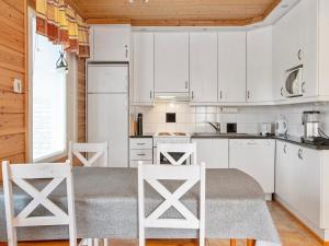a kitchen with white cabinets and a table and chairs at Holiday Home Velho 2 by Interhome in Saariselka
