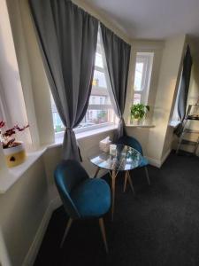 ロンドンにあるCozy place to stay in Londonのテーブルと椅子2脚、窓が備わる客室です。