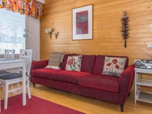 uma sala de estar com um sofá vermelho e paredes de madeira em Holiday Home Rautulampi h 24 by Interhome em Saariselka