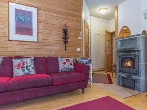 sala de estar con sofá rojo y chimenea en Holiday Home Rautulampi h 24 by Interhome, en Saariselkä