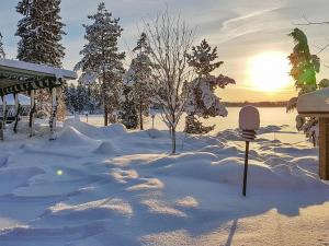 um quintal coberto de neve com o pôr do sol ao fundo em Holiday Home Riemurahi by Interhome em Pertunmaa