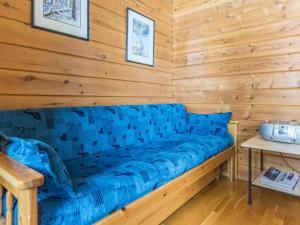 - un canapé bleu dans une chambre dotée d'un mur en bois dans l'établissement Holiday Home Urupää d 17 by Interhome, à Saariselka