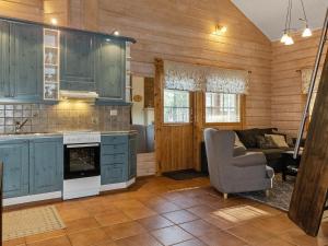 a kitchen with blue cabinets and a chair and a couch at Holiday Home Puuhapirtti 1 by Interhome in Sirkka