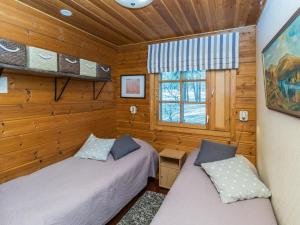 two beds in a room with wooden walls and a window at Holiday Home Saaga by Interhome in Saariselka