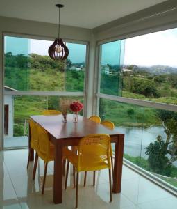een eettafel met gele stoelen en een groot raam bij Aconchego da serra in Bezerros