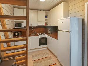 a kitchen with white cabinets and a refrigerator at Holiday Home Ukkorinne mökki by Interhome in Hyrynsalmi