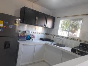 een keuken met witte kasten en een roestvrijstalen koelkast bij Piantini Houses in Coveñas