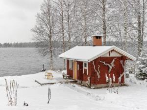 a small cabin in the snow next to a lake at Holiday Home Käpälämäki by Interhome in Raanujärvi