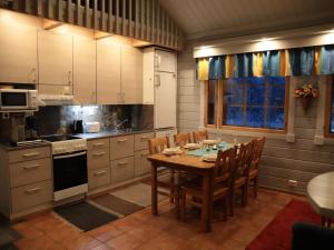 a kitchen with a wooden table and chairs and a kitchen with white cabinets at Holiday Home Tunturikoivu a1 by Interhome in Saariselka
