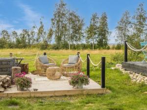 a patio with wicker chairs and flowers in a field at Holiday Home Peuhu a4 by Interhome in Oulunsalo
