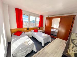 a small room with two beds and red curtains at MEQUEDO CALDEREROS 25 in Alcañiz
