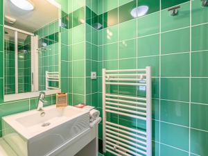 Baño de azulejos verdes con lavabo y espejo en Apartment Le Château de Kergonano-13 by Interhome en Baden