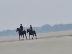 zwei Leute reiten auf Pferden am Strand in der Unterkunft Opal'In in Gravelines