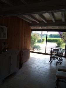 a room with a table and chairs and a large window at Ferme de la NOE in Sérigny