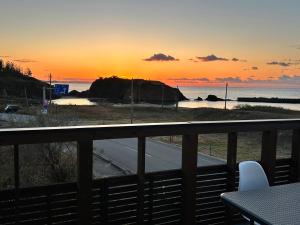 desde un balcón con vistas a la playa al atardecer en 海宿ニシノヤ 